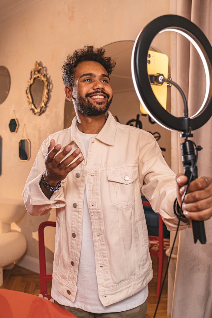 Smiling vlogger using a ring light in a cozy indoor setting.